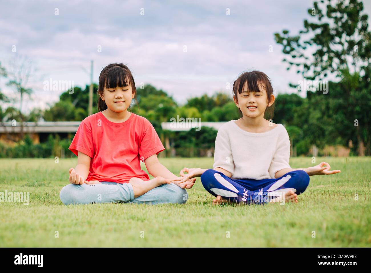 Kindermeditation mit Yoga-Pose auf grünem Grasfeld. Aktivitäten im Freien für Kinder, Yoga-Übungen, Kinder können lernen, wie man trainiert. Stockfoto