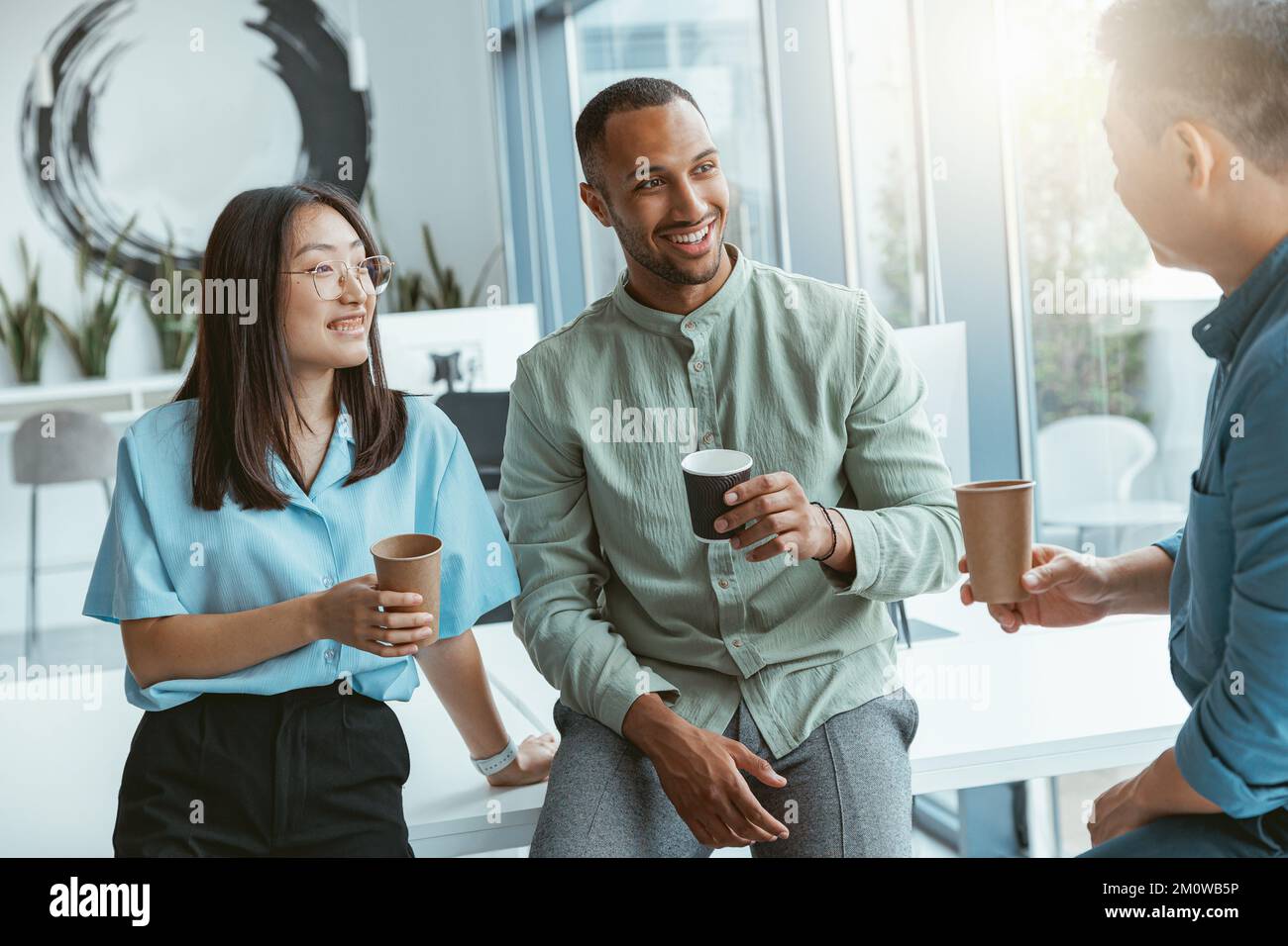 Lächelnde Gruppe multiethnischer Kollegen, die während der Pause Kaffee trinken und sich unterhalten Stockfoto