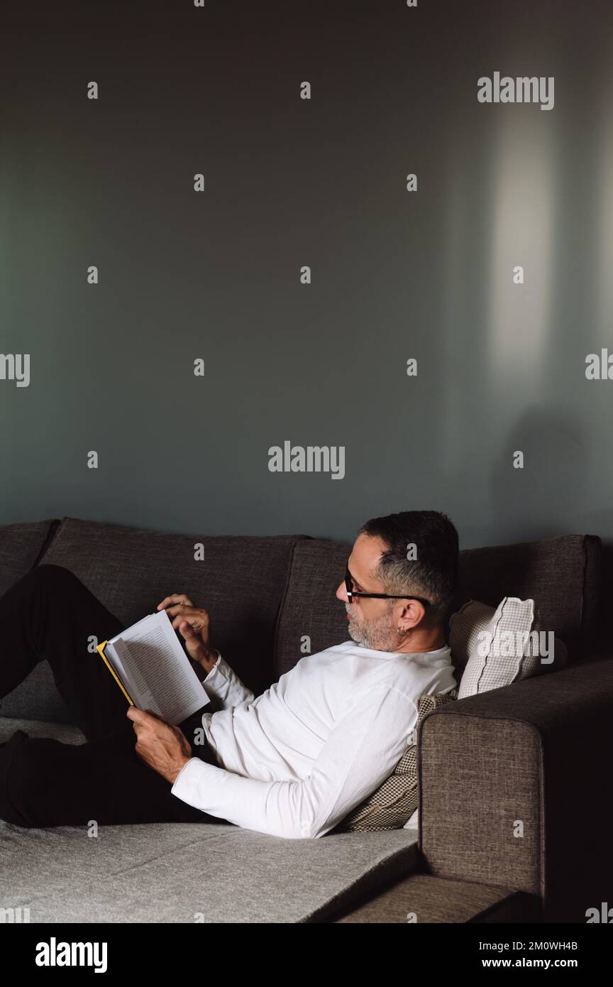 Mann liest Buch auf der Couch. Stockfoto