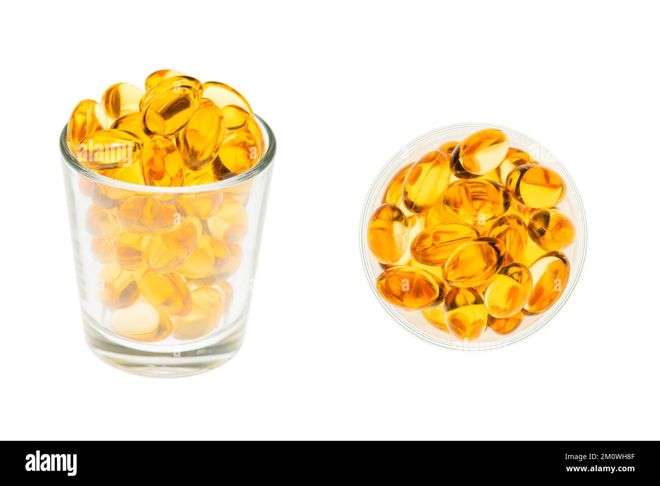 Nahaufnahme von Fischölkapseln mit Omega-3 und Vitamin D in einem Glasbecher, isoliert auf weißem Hintergrund Stockfoto