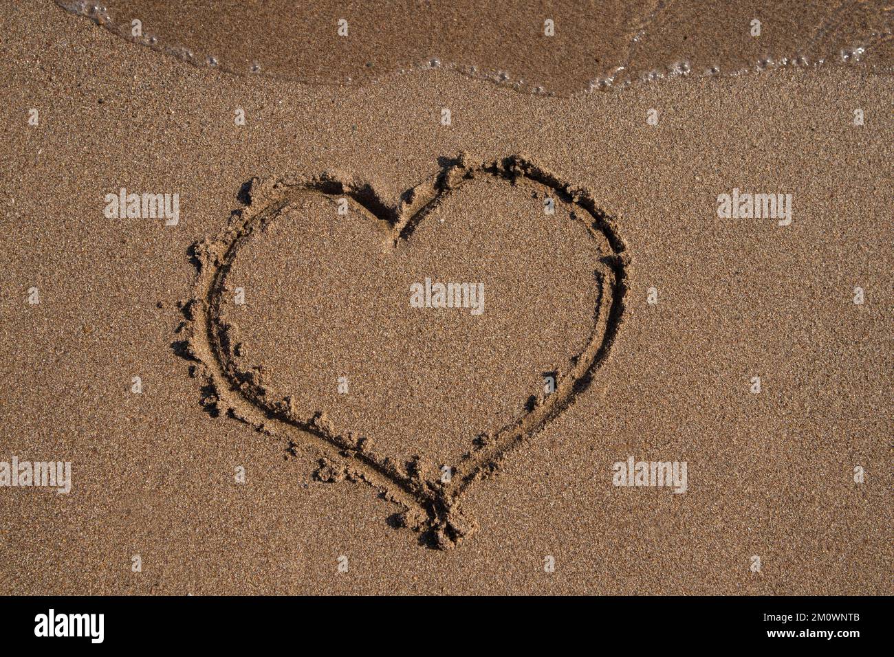 Strand. Ein Herz auf den Sand zu zeichnen, eine Welle. Seeufer, Postkarte mit Kopierraum. Stockfoto