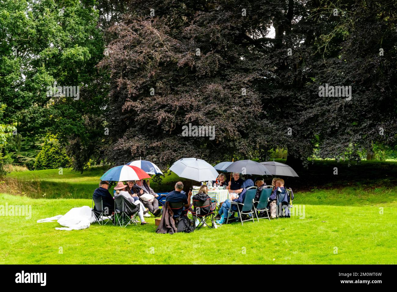 Eine Gruppe von Personen, die ein Picknick im Regen machen, Hever Castle, Kent, Großbritannien. Stockfoto