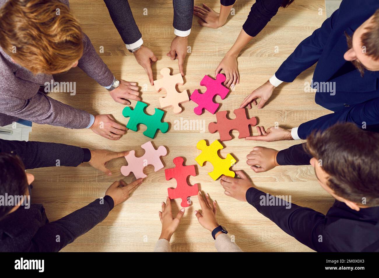 Farbige Puzzleteile, die Geschäftsleute beim Teamaufbau miteinander verbinden. Stockfoto