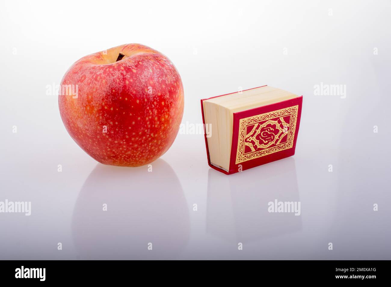 Roter Apfel und islamisches Heiliges Buch Koran in Minigröße Stockfoto