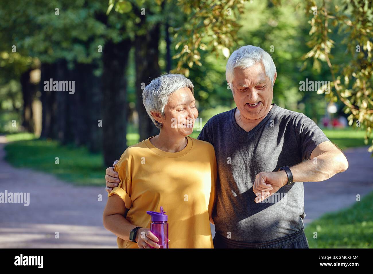 Gealtertes Paar trainieren im Sommerpark tragen watch Check Daten mit Anwendung Pflege über Gesundheit. Sportlich aktiv im Ruhestand Ehepartner Lebensstil mit modernen Stockfoto