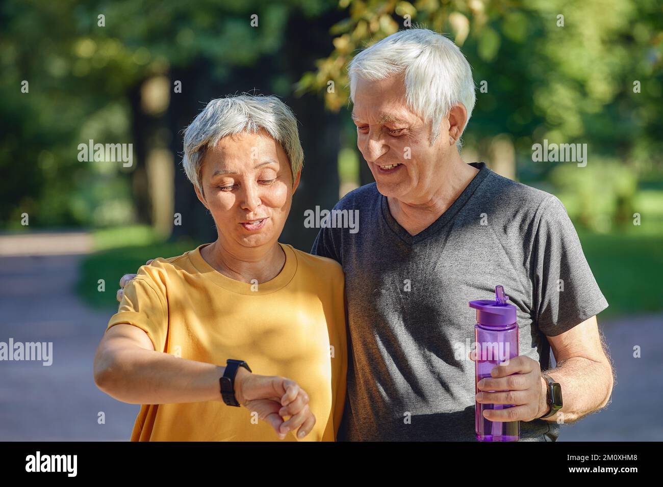 Gealtertes Paar trainieren im Sommerpark tragen watch Check Daten mit Anwendung Pflege über Gesundheit. Sportlich aktiv im Ruhestand Ehepartner Lebensstil mit modernen Stockfoto