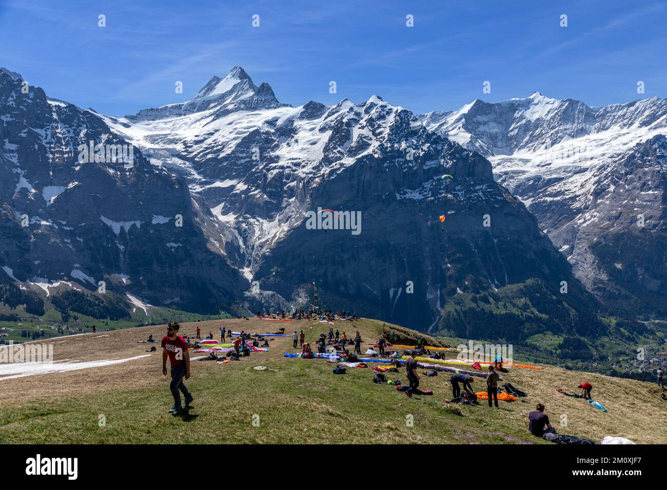 Eine große Gruppe von Gleitschirmfliegern wartet auf den ersten Berg in der Schweiz auf die perfekten Windbedingungen, damit sie in den Himmel fliegen können. Stockfoto