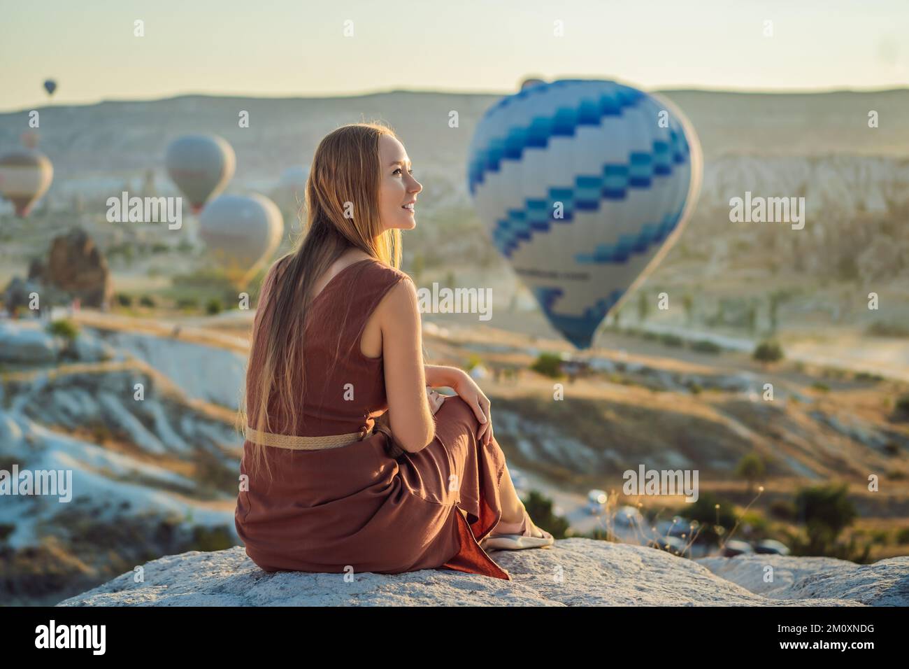 Eine Touristin, die Heißluftballons in Kappadokien, Türkei, ansieht. Happy Travel in Turkey Concept. Eine Frau auf einem Berggipfel, die eine wunderbare Aussicht genießt Stockfoto