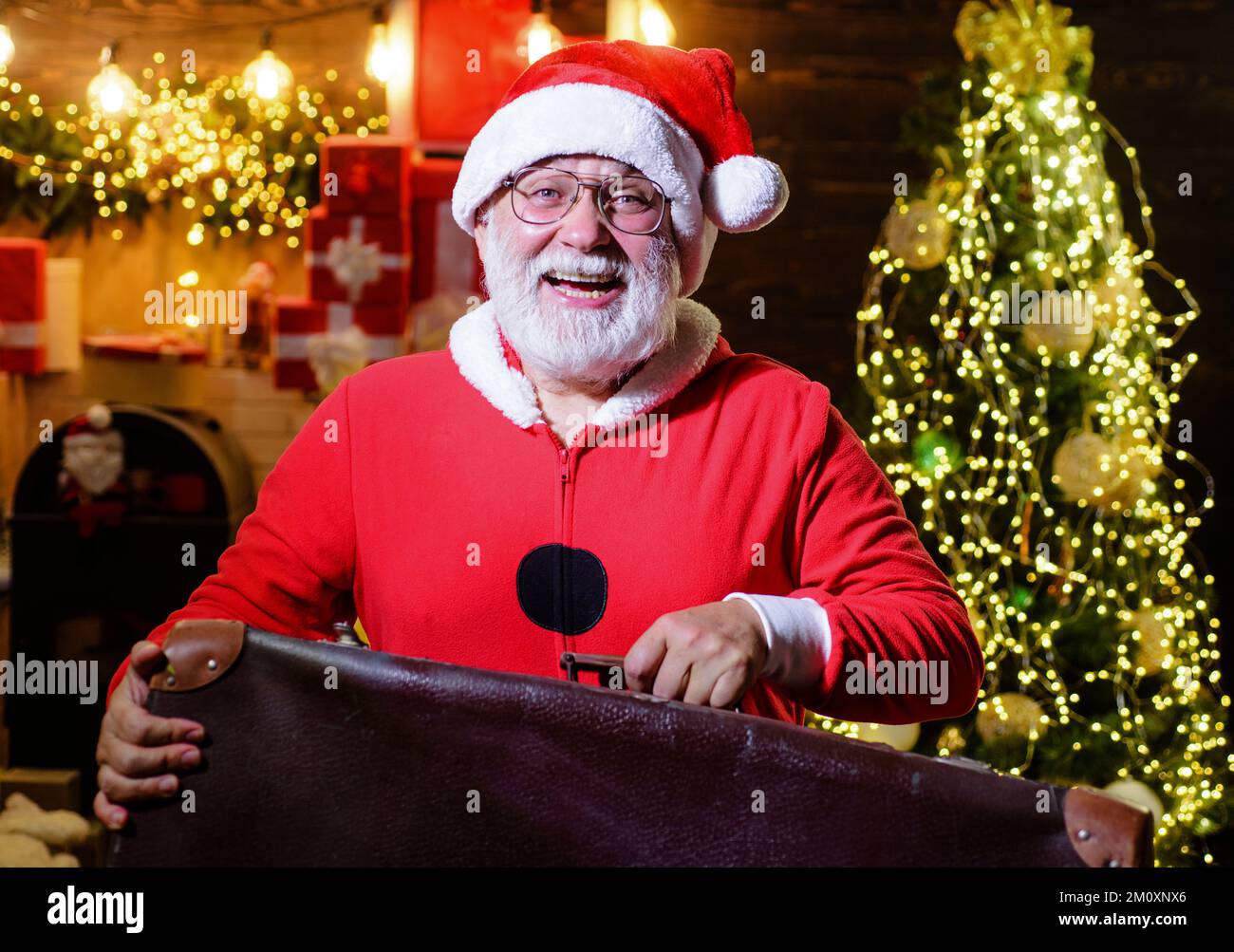 Der Weihnachtsmann mit dem alten Lederkoffer. Neujahr- oder Weihnachtsreisen. Ein Mann mit Gepäck, der unterwegs ist. Stockfoto