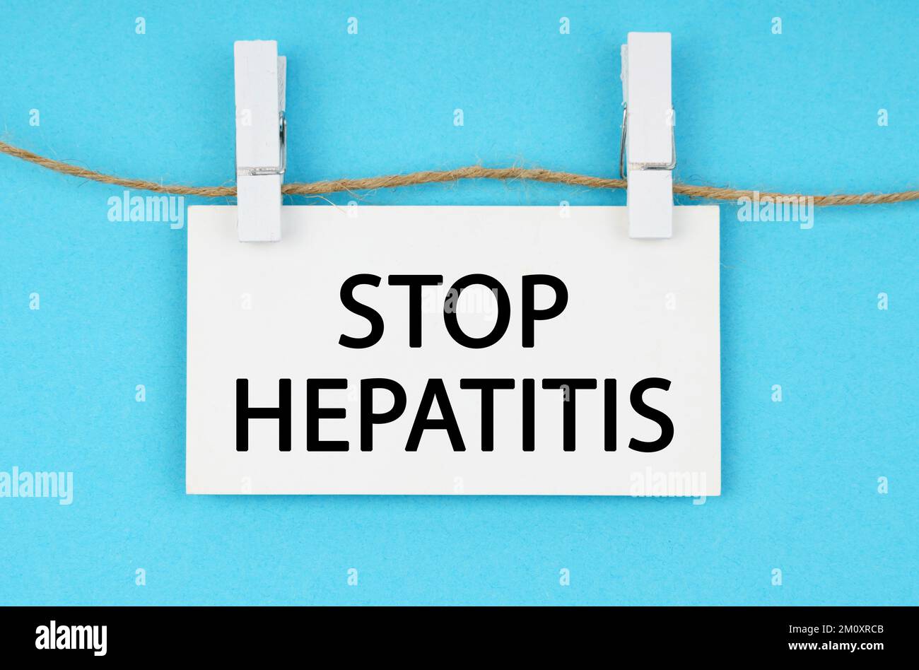 Medizin und Gesundheitskonzept. Auf blauem Hintergrund hängt eine weiße Plakette an einem Seil mit der Inschrift - STOPPT HEPATITIS Stockfoto