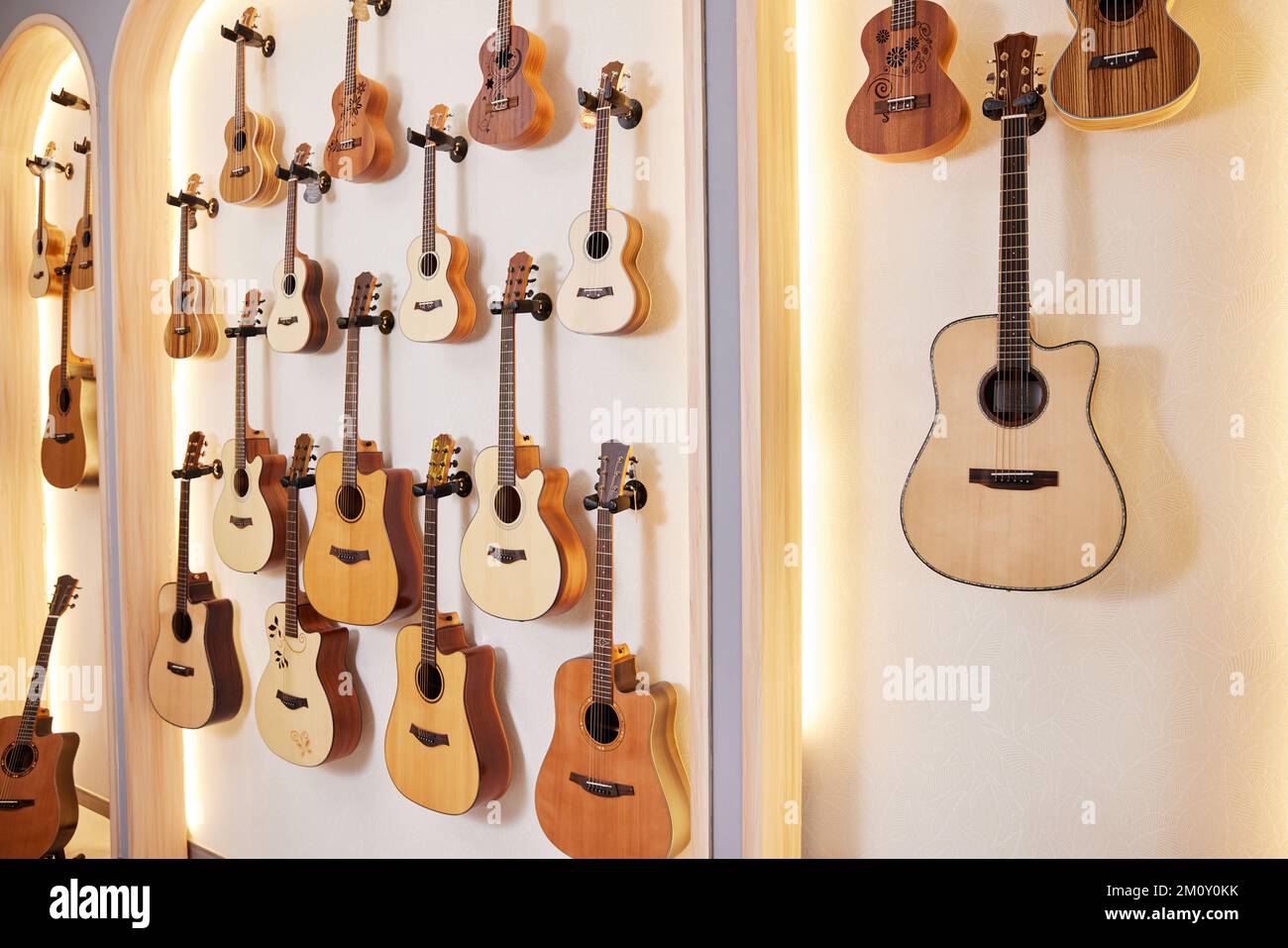 Eine Wand voller verschiedener Gitarren; Gitarrenverkauf; Sammlung von Musikinstrumenten Stockfoto