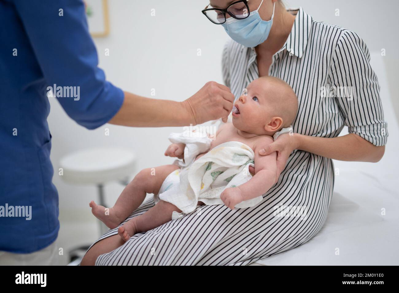 Kinderarzt mit oraler Impfung gegen Rotavirusinfektion beim Kleinkind in Gegenwart seiner Mutter. Kindergesundheit und Krankheitsprävention. Stockfoto