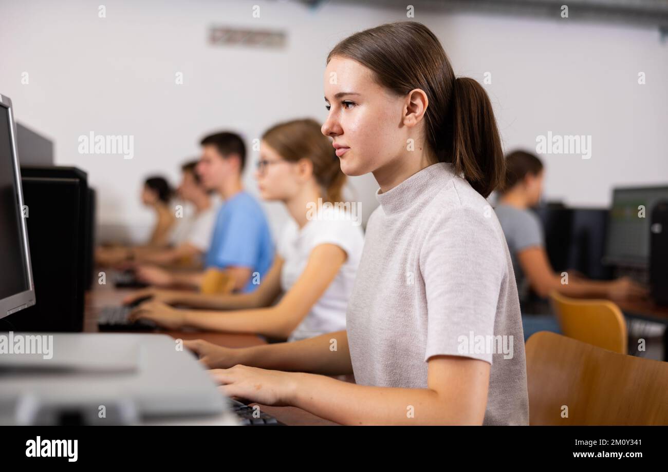 Interessierte Teenagerin, die mit Klassenkameraden studiert Stockfoto