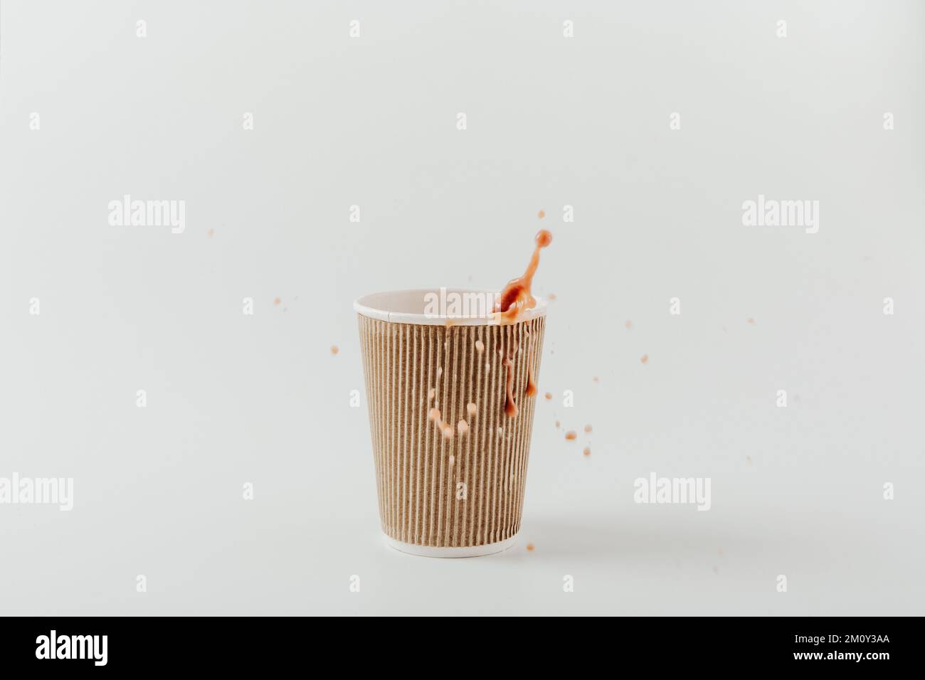 Pappbecher mit heißem Getränk und Spritzer. Weißer Hintergrund. Kaffee, Latte, Cappuccino, Kakao. Einweg-Pappbecher. Recycling und umweltfreundliches Konzept. Stockfoto