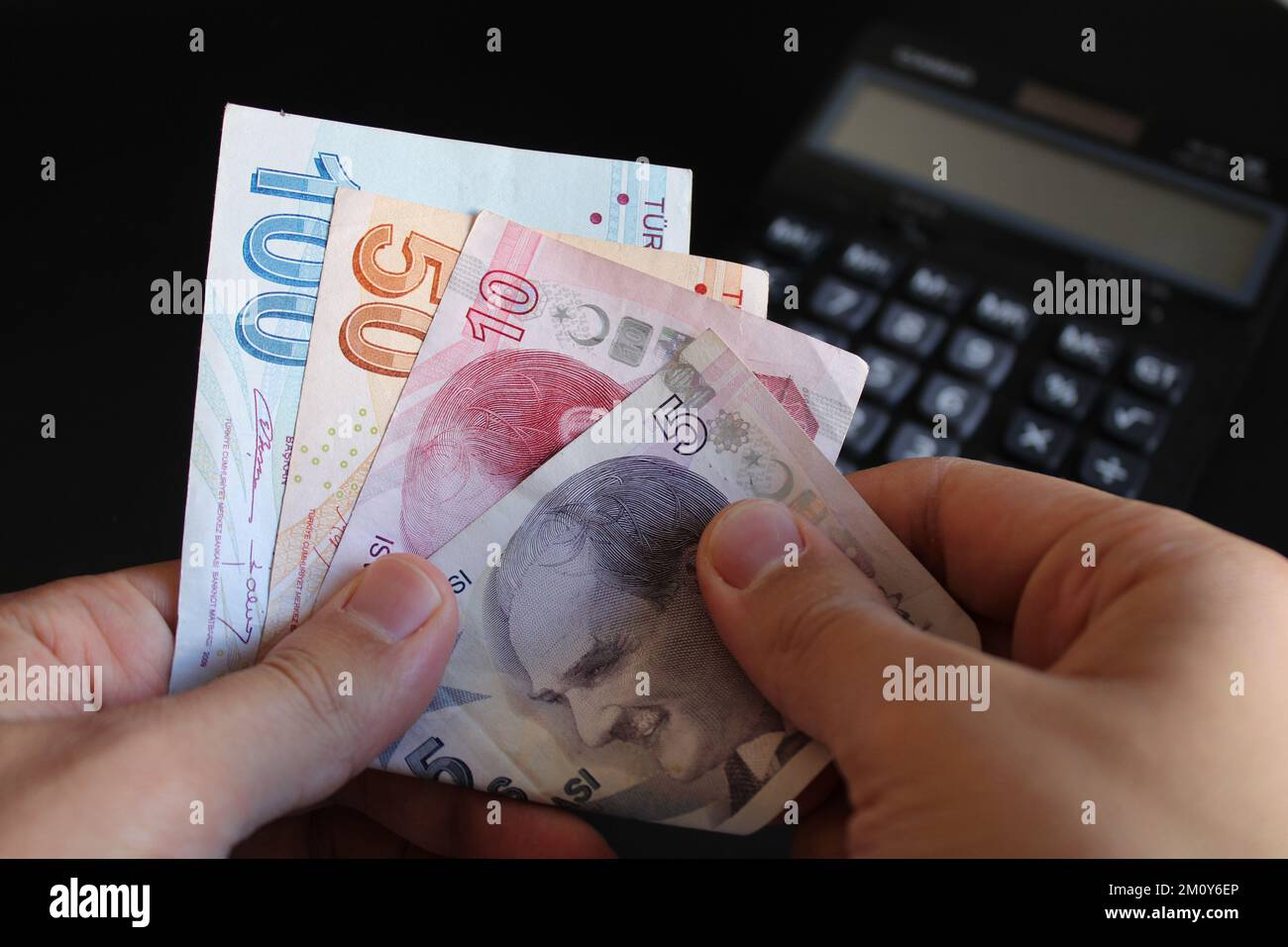 Ein Mann, der türkisches Geld mit der Hand zählt. Türkische Lira-Banknoten. Die Papierwährung der Türkei.Calculator im Hintergrund. Für Steuern und Wandernachrichten. Stockfoto