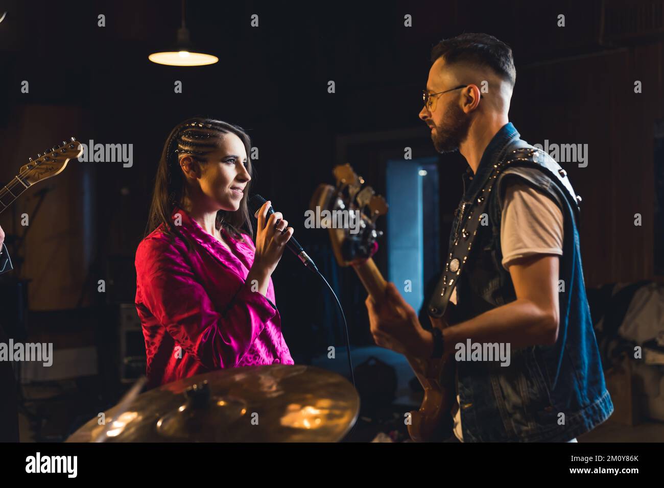 Eine Frau, die mit der Musikband singt, Gitarren und Schlagzeug spielt und sie begleitet. Hochwertiges Foto Stockfoto