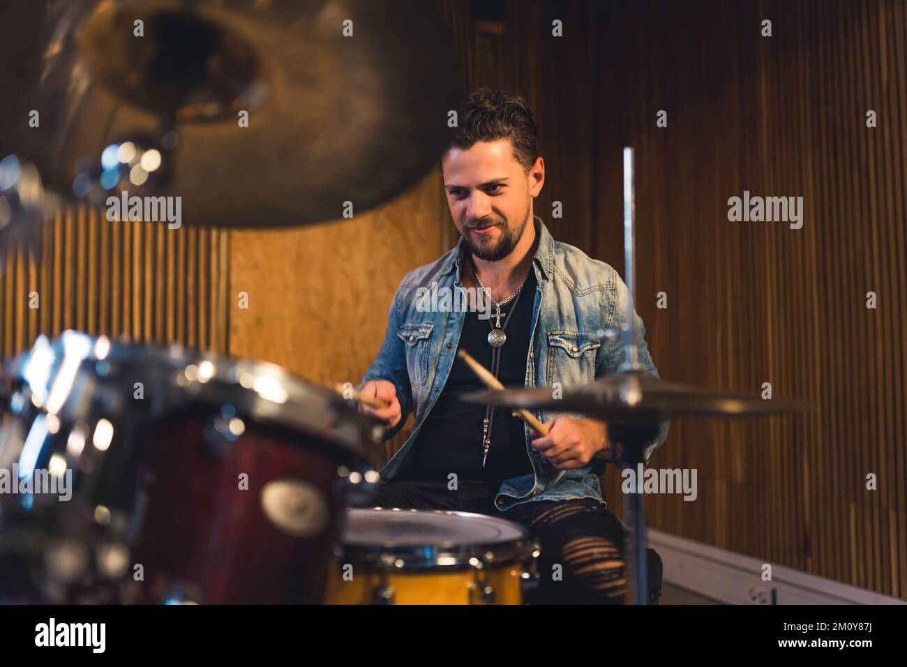 Ein junger Musiker, der in einem Studio Schlagzeug spielt. Hochwertiges Foto Stockfoto