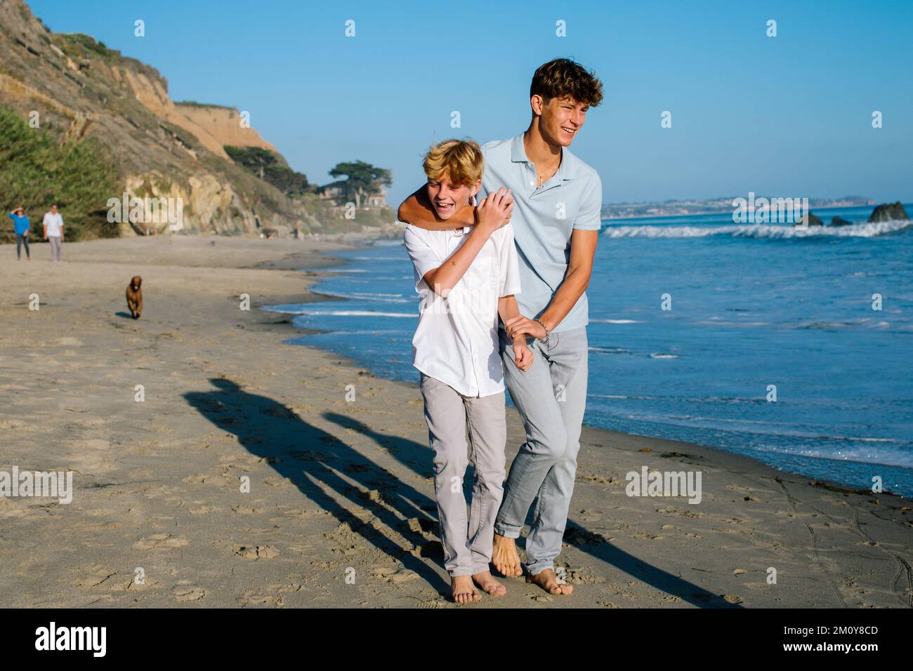Brüder Laufen Am Strand, Während Der Ältere Bruder Sich Verspielt Geschwister Schnappt Stockfoto