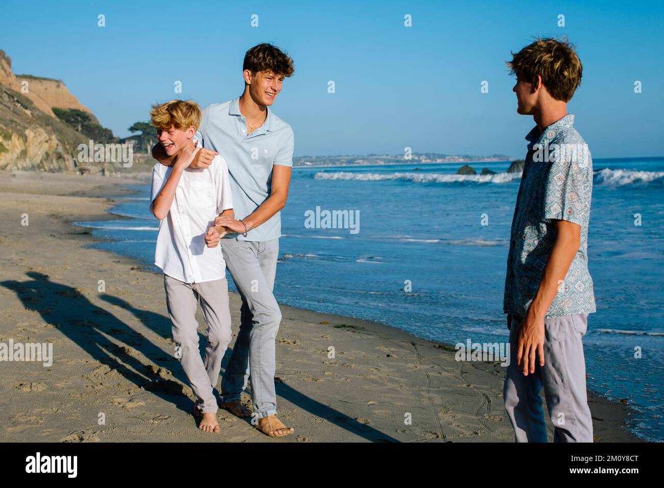 Der Ältere Bruder Würgt Seinen Jüngeren Bruder Verspielt Am Strand Stockfoto