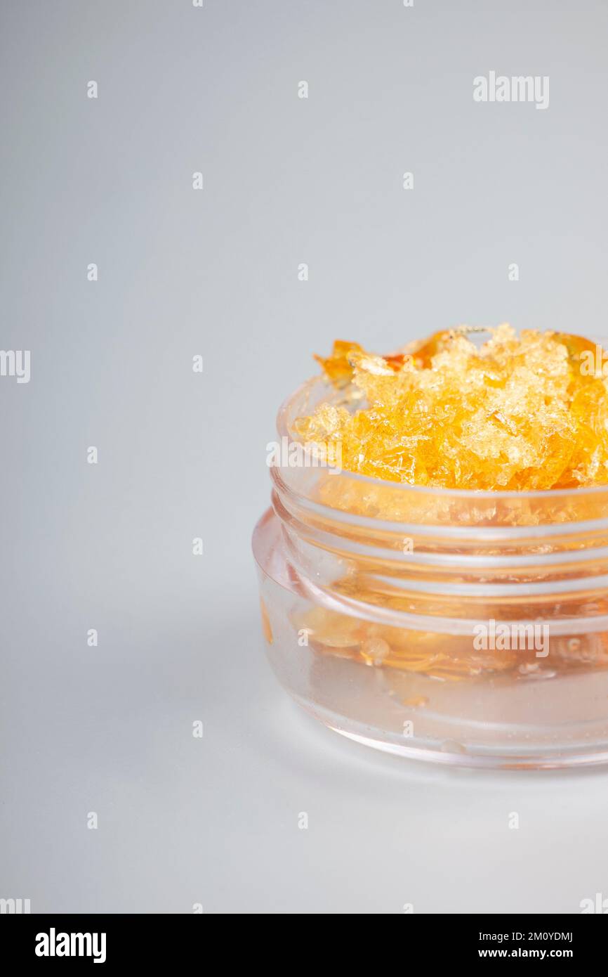 goldener thc-Kristall, Glasbehälter mit Krümeln aus Cannabiswachs und Kopierraum. Stockfoto