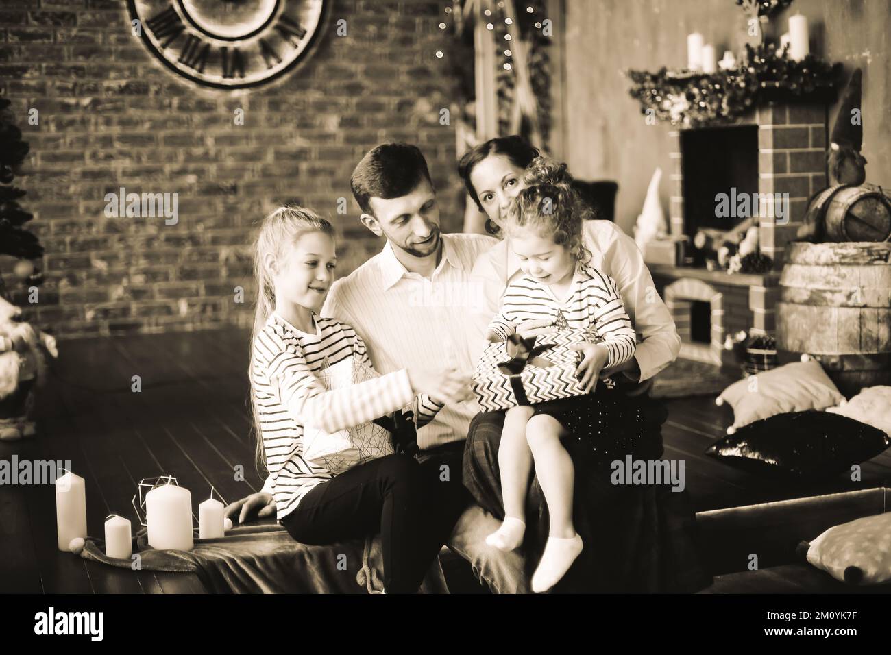 Glückliche Familie mit Weihnachtsgeschenken in einem gemütlichen Wohnzimmer. Schwarzweißfoto Stockfoto