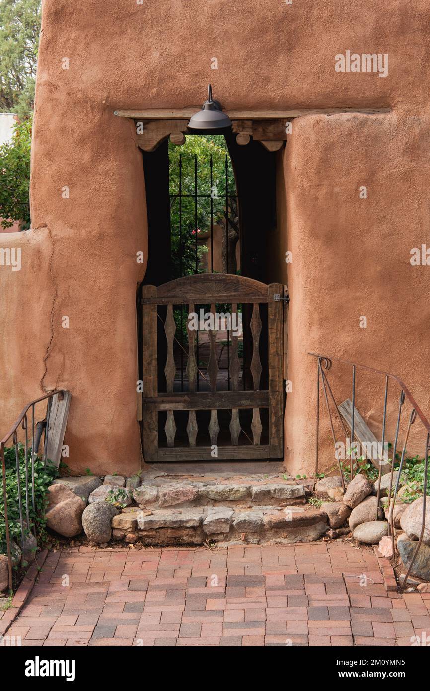 Rustikales Holztor am Eingang zum Garten durch eine lehmwand in Santa Fe, New Mexico Stockfoto