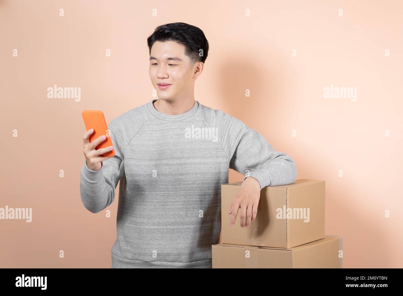 Asiatischer männlicher Geschäftsführer, der die Paketkartons per Handy überprüft. Stockfoto