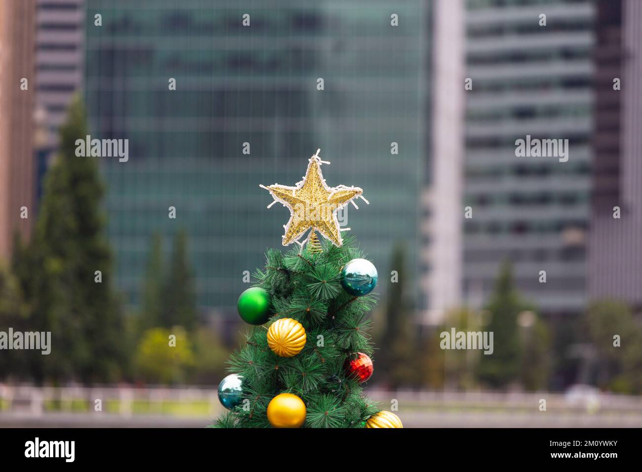 Nahansicht an der Spitze des geschmückten Weihnachtsbaums vor städtischer kommerzieller Architektur. Singapur. Stockfoto