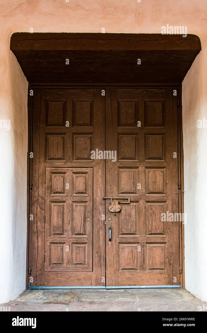 Riesige, alte, rustikale Holztür in dicken lehmwänden in einem historischen Gebäude in Santa Fe, New Mexico Stockfoto