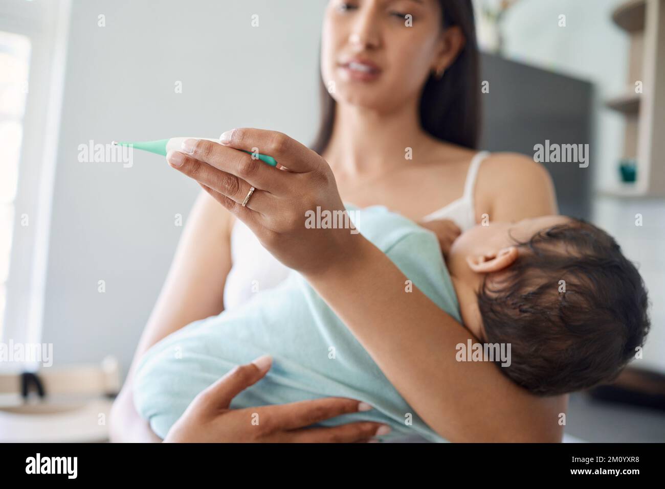 Ich bin mir nicht sicher, ob ich mir Sorgen machen sollte oder nicht. Eine Mutter, die zu Hause die Temperatur ihres Babys misst. Stockfoto