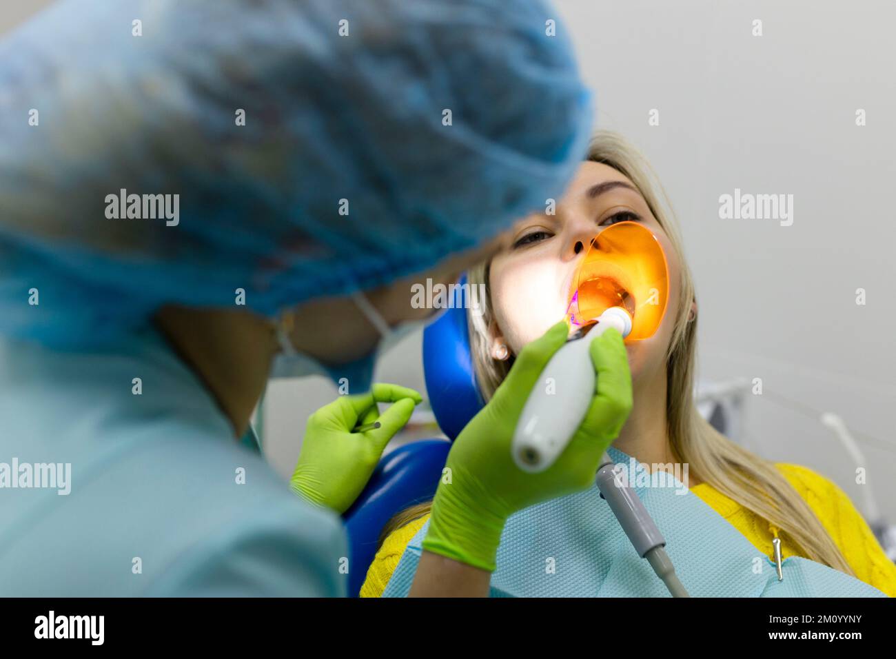 Medizin, Zahnheilkunde und Gesundheitskonzept, Zahnarzt mit zahnärztlicher Härte-UV-Lampe an den Zähnen des Patienten. Stockfoto
