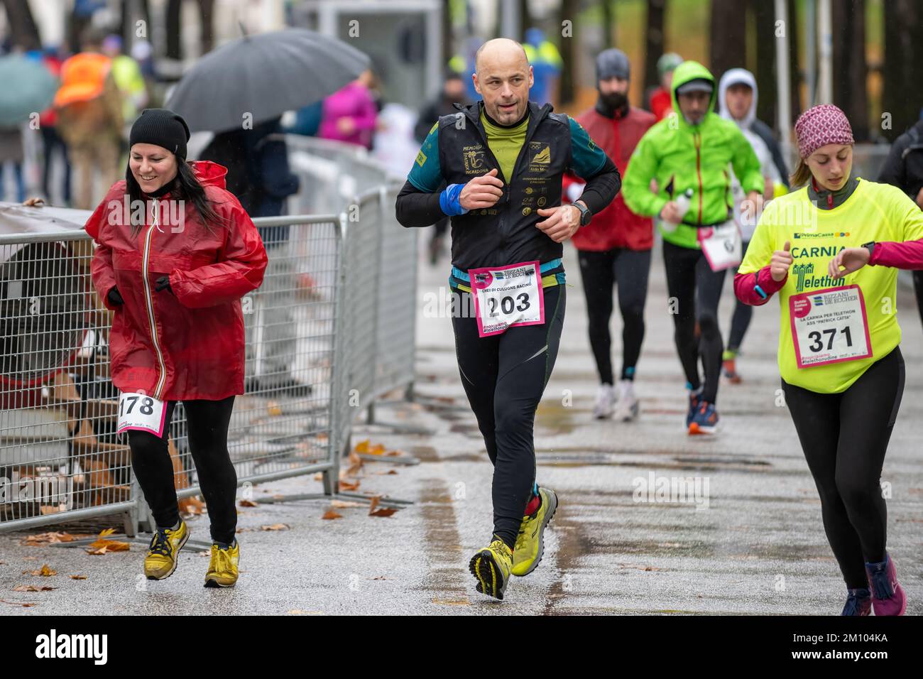 Sportler, die anlässlich des Telethon-Marathon-Staffelrennen unter Regen laufen. Udine City, Italien. 4. Dezember 2022. Stockfoto