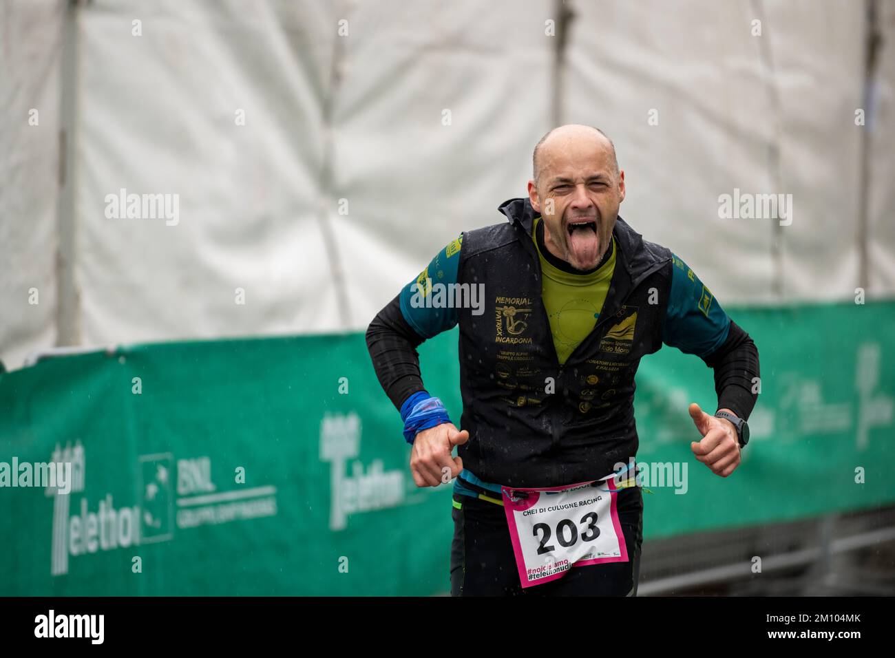 Sportler, die anlässlich des Telethon-Marathon-Staffelrennen unter Regen laufen. Udine City, Italien. 4. Dezember 2022. Stockfoto