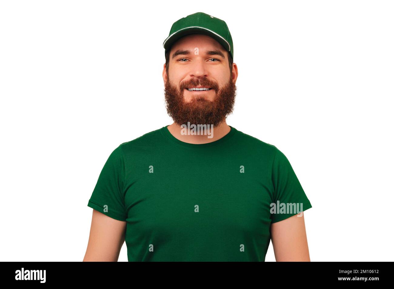 Das Studio-Porträt eines gutaussehenden bärtigen Mannes trägt eine grüne Kurieruniform mit einer Mütze. Stockfoto