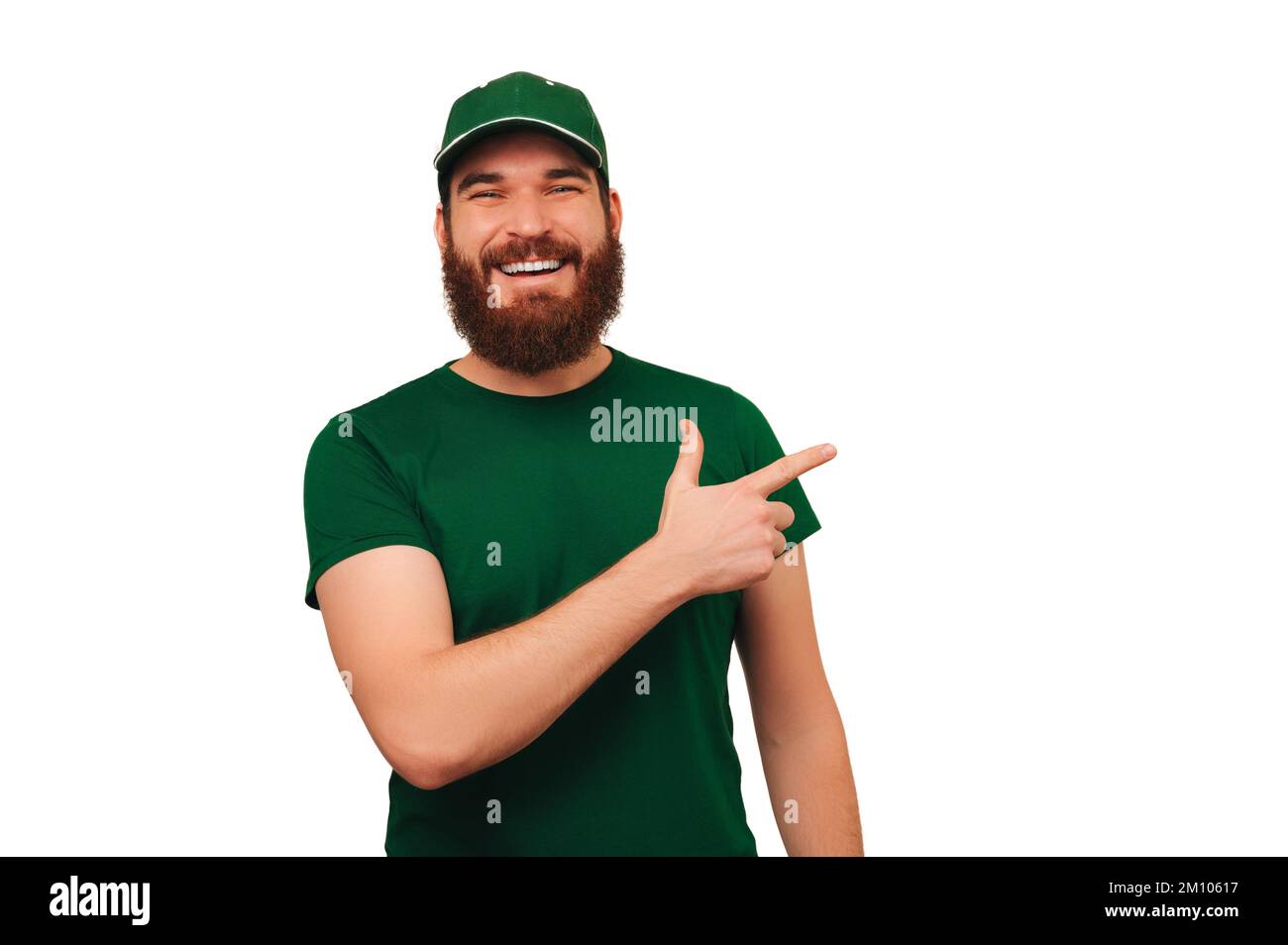 Ein glücklicher bärtiger Mann mit grüner Mütze und T-Shirt als Kurier auf weißem Hintergrund. Stockfoto