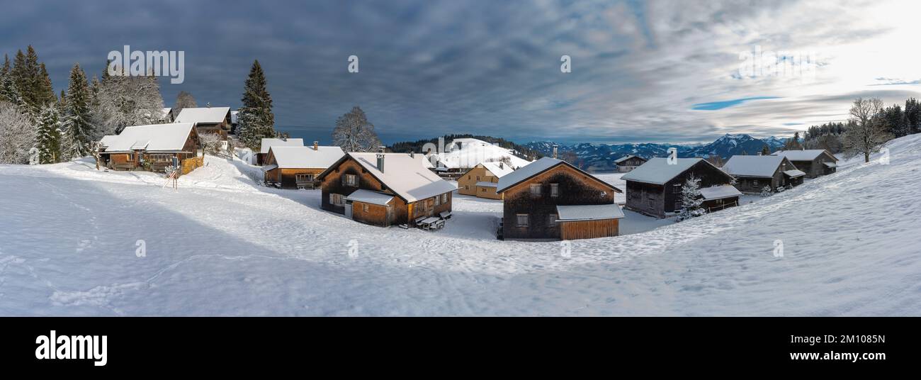 Winterpanorama vom Bödele bei Dornbirn, mit frisch verschneiten alten Alphäusern aus Holz, mit schneebedeckten Bergen im Hintergrund Stockfoto