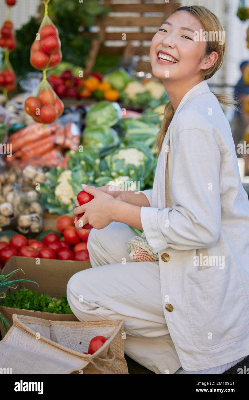 Asiatische Frau, Supermarkt- und Lebensmitteleinkäufe und Tomaten, Kunde und Einzelhandel, frische Gemüseprodukte und Lebensmittel im Geschäft kaufen. Junge, glückliche Frau Stockfoto