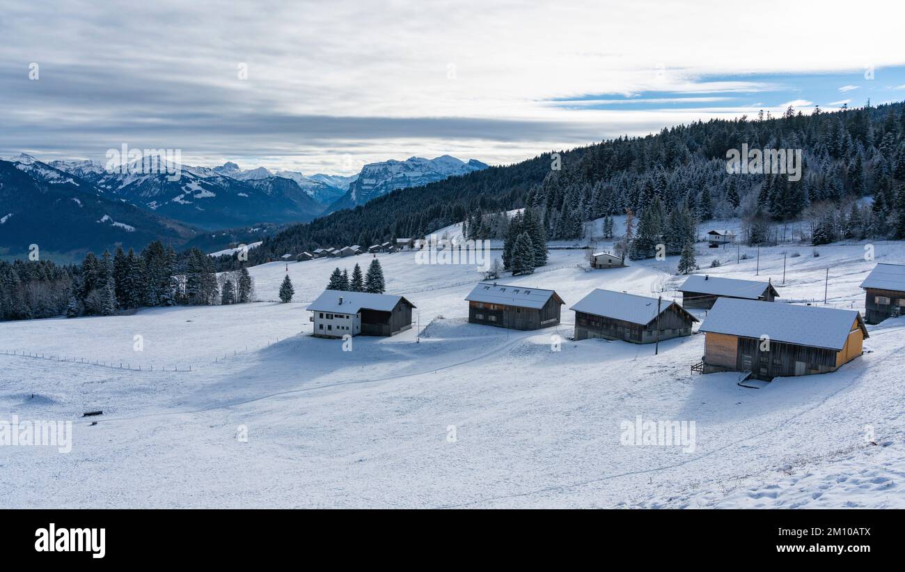 Winterpanorama vom Bödele bei Dornbirn, mit frisch verschneiten alten Alphäusern aus Holz, mit schneebedeckten Bergen im Hintergrund Stockfoto