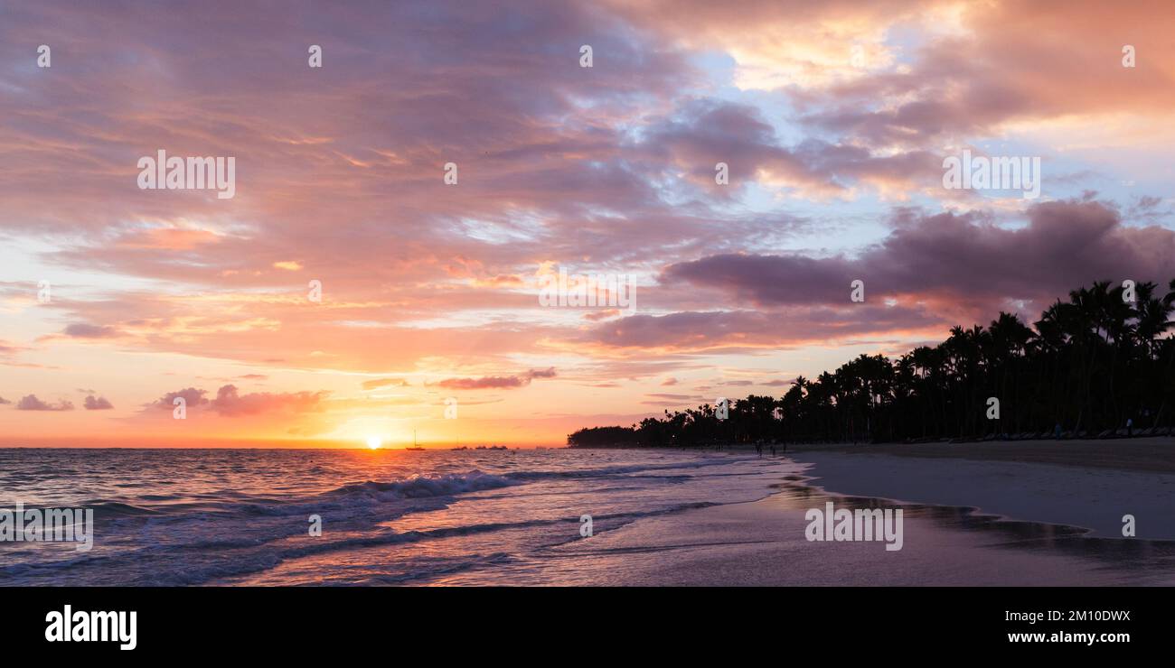 Atlantikküste bei Sonnenaufgang, Bavaro Strand, Dominikanische Republik. Panorama Küstenlandschaft mit aufstrebender Sonne, Palmen Silhouetten in Farbe Stockfoto