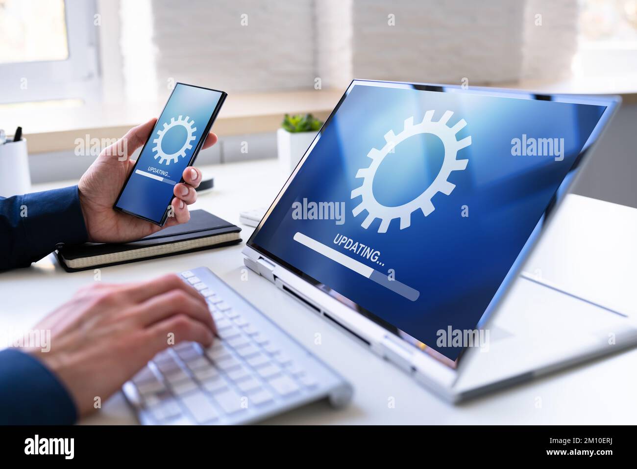 Mann, Der Software-Update Auf Mobiltelefon Und Laptop Macht Stockfoto