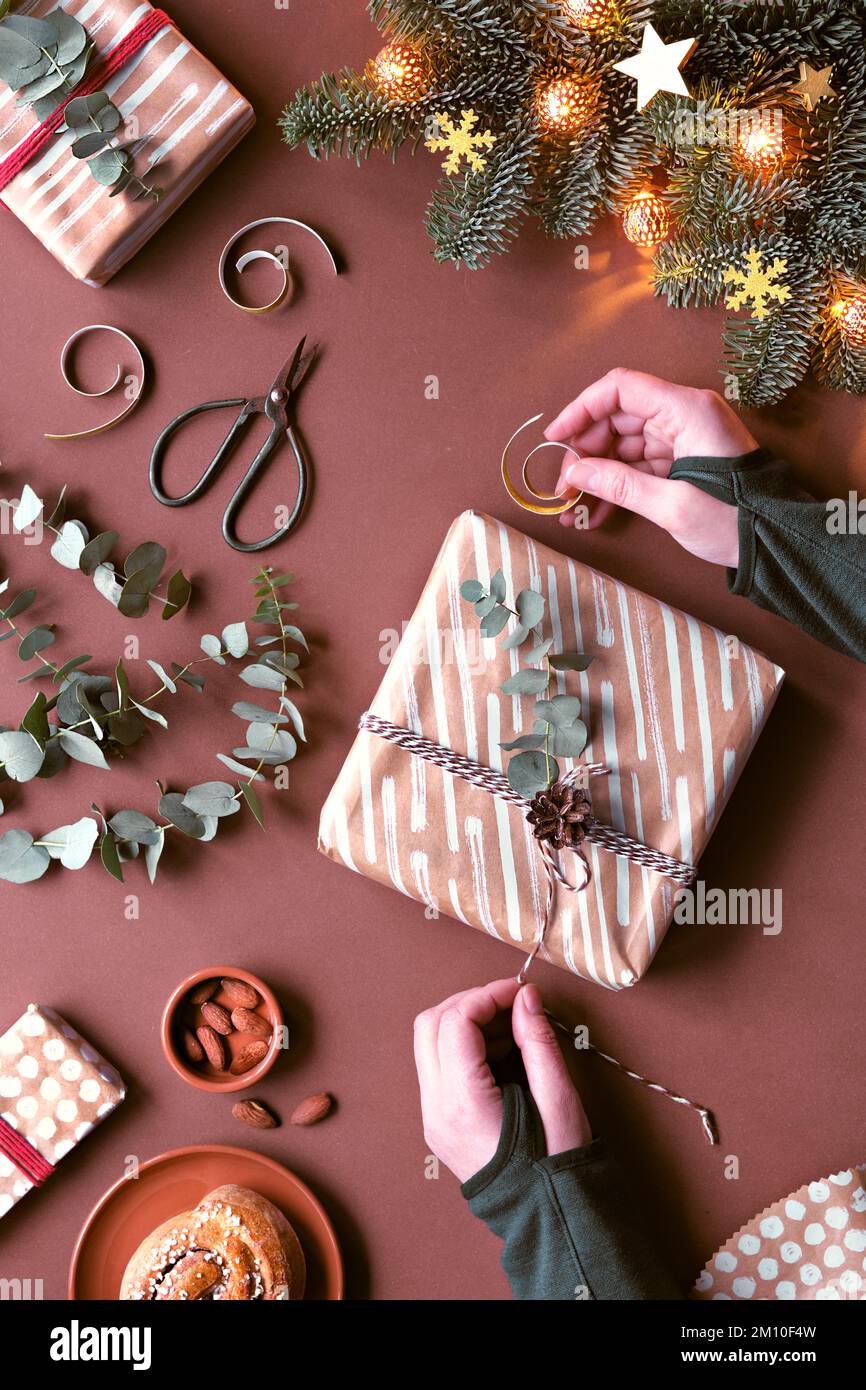 Brauner Weihnachtshintergrund mit Geschenkverpackung für Weihnachten. Flach liegend mit Marzipan-Süßigkeiten, Geschenken, Eukalyptus, Sternen, Zimtbrötchen. Draufsicht Stockfoto