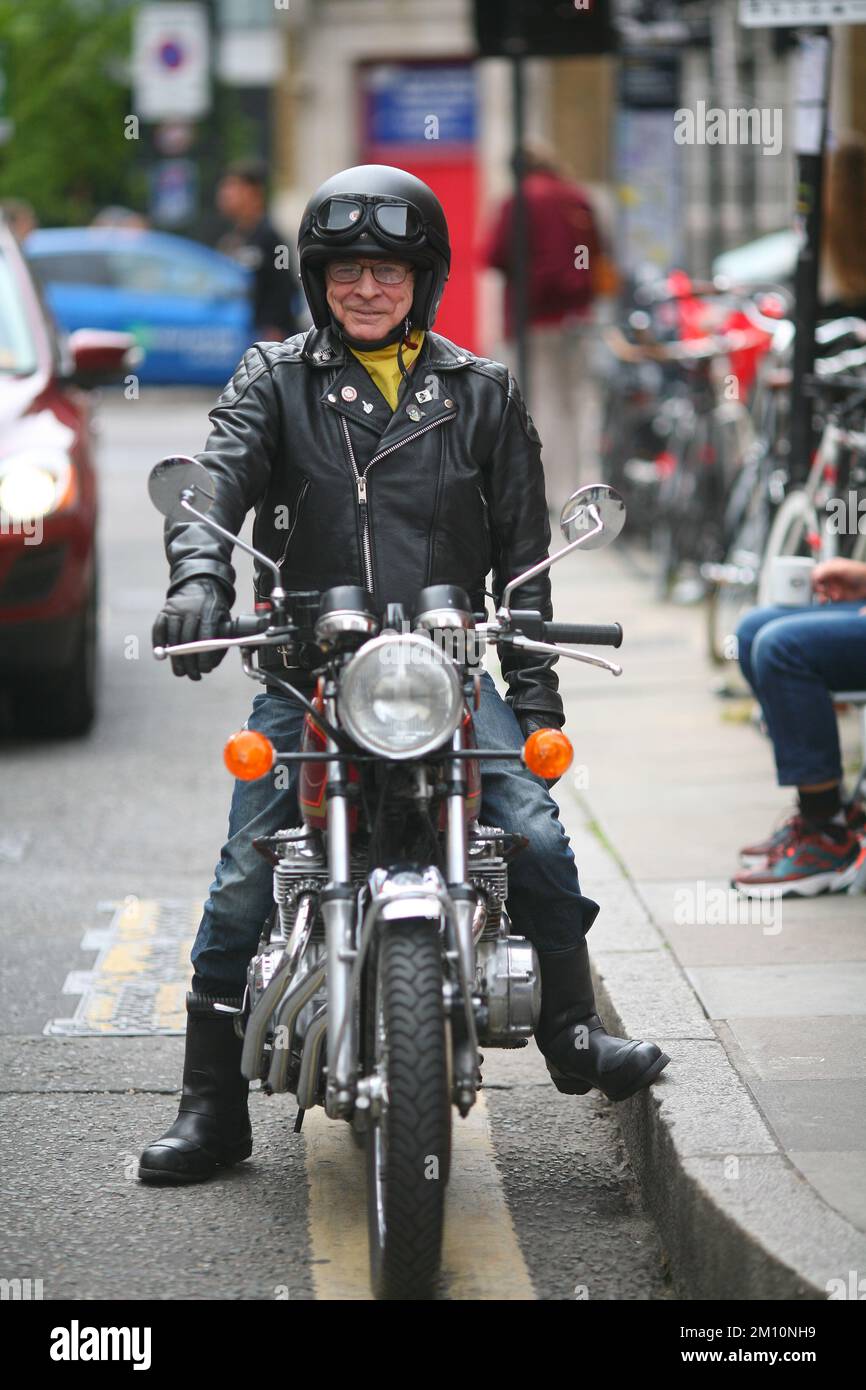 Motorradfahrer auf dem Motorrad vor der Brick Lane in East London, trägt klassische Motorradjacke, Jeans und Biker-Stiefel Stockfoto