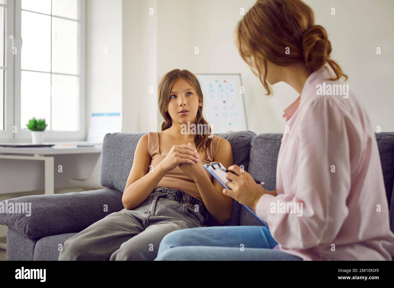 Teenager, die auf dem Sofa sitzt und Fragen beantwortet, die Therapeutin oder Psychologin stellen Stockfoto