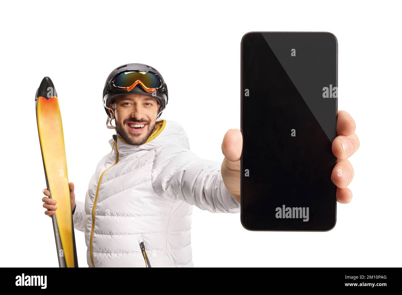 Glücklicher Skifahrer, der ein Smartphone vor der Kamera hält, isoliert auf weißem Hintergrund Stockfoto