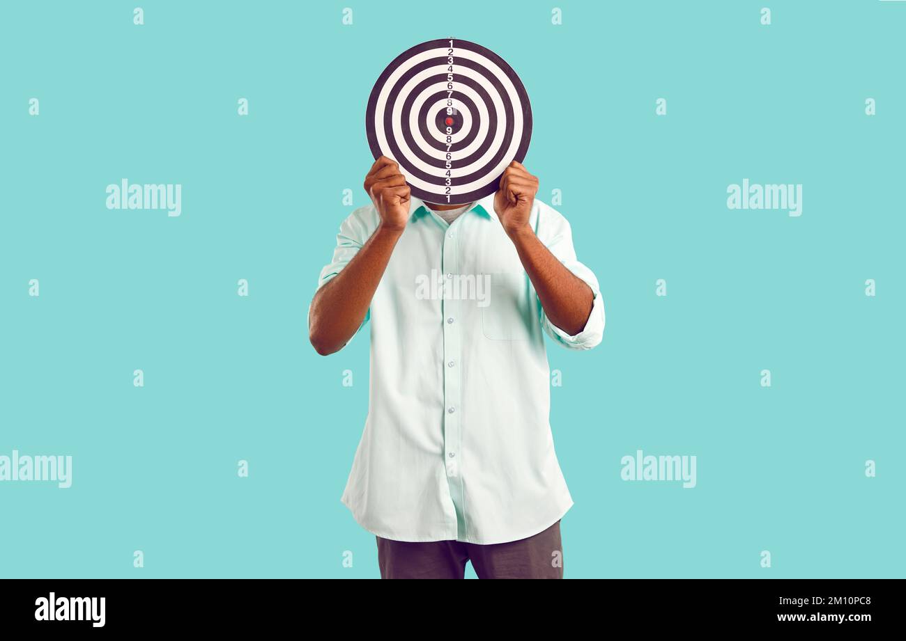 Ein anonymer Mann versteckt sein Gesicht hinter dem Dartboard und symbolisiert die Auswahl der Zielgruppe oder der zielgerichteten Werbung Stockfoto