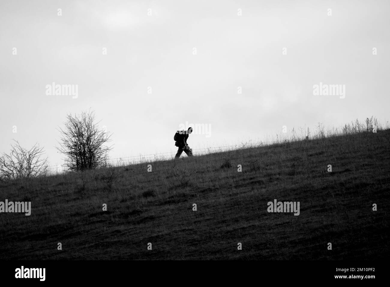 Silhouette eines Soldaten der britischen Armee, der einen steilen Hügel mit 40kg bergen über offene Landschaften in Wiltshire UK hinaufsteigt Stockfoto