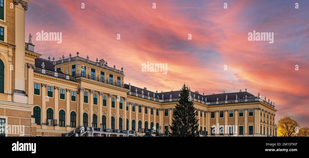 WIEN, ÖSTERREICH - 25. NOVEMBER 2022: Schloss Schönbrunn und sein Weihnachtsbaum bei Sonnenuntergang. Traditionelles Panorama des Weihnachtsmarkts im Schloss Sissi Stockfoto