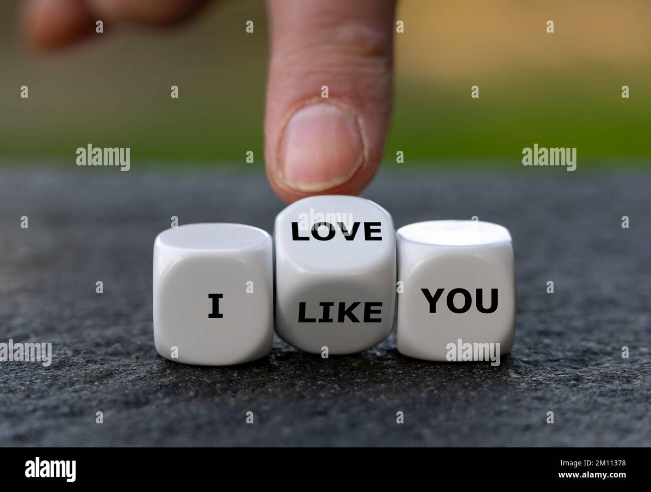 Die Hand würfelt und ändert den Ausdruck „Ich mag dich“ in „Ich liebe dich“. Stockfoto