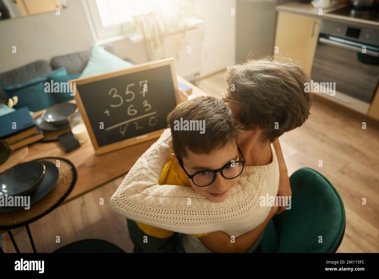 Großmutter hilft dem Kind, Mathe in der Küche zu lernen Stockfoto