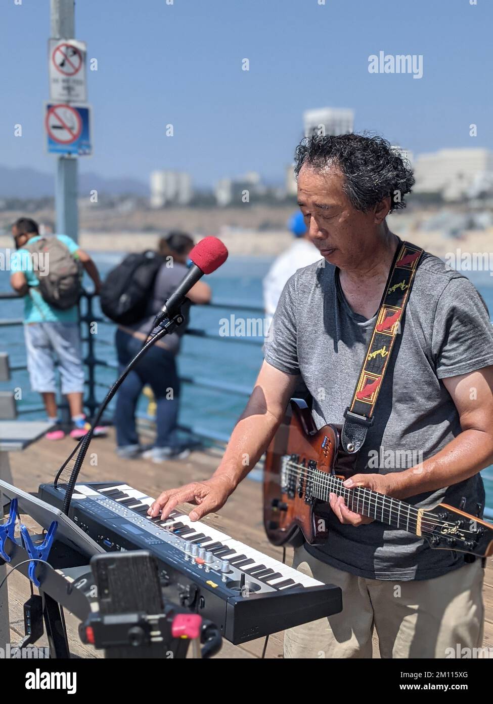 Eine vertikale Aufnahme eines Straßenmusikers, der an einem sonnigen Tag am Santa Monica Pier auftritt Stockfoto